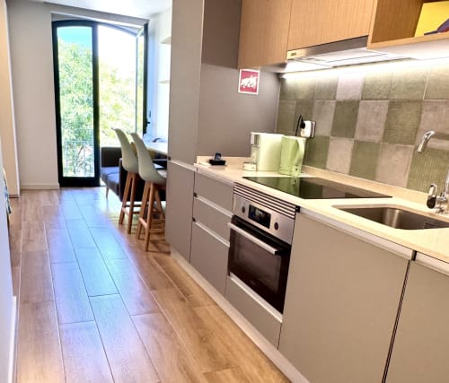 Cuisine moderne avec électroménagers en acier inoxydable, dosseret en carrelage vert, coin repas et vue sur balcon au RIA CENTRUM Aveiro