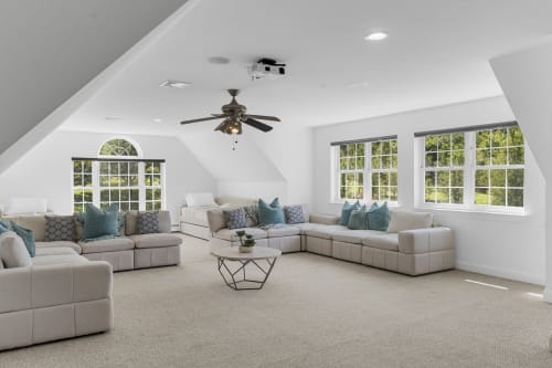 Spacious modern villa living room at Malkita Homes in Woodbury with cream sectional seating, mountain views, and ceiling fan