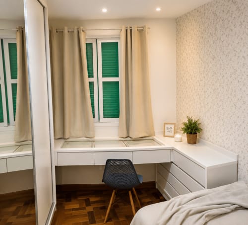 Quarto moderno com escrivaninha branca, cadeira preta e janelas com persianas verdes no apartamento CSS em Maringá