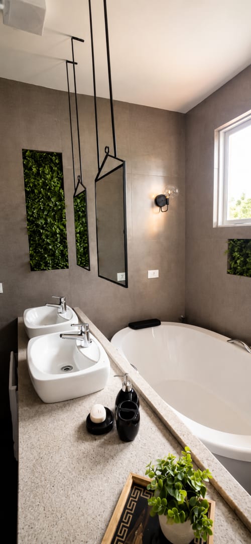 Banheiro moderno no apartamento CSS em Maringá com pias duplas, banheira, espelhos suspensos, painéis verdes e iluminação natural
