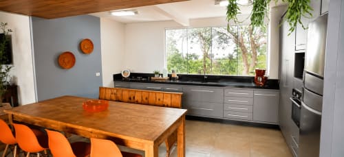 Cozinha e sala de jantar modernas em apartamento de Maringá com mesa de madeira, cadeiras laranja, armários cinza e vista da cidade