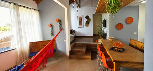 Sala de jantar moderna em Maringá com mesa de madeira, cadeiras laranja, vista da cidade pela janela e parede decorativa