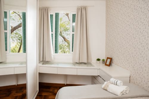 Quarto brilhante no apartamento CSS em Maringá com vista da cidade, penteadeira branca, venezianas verdes e comodidades modernas