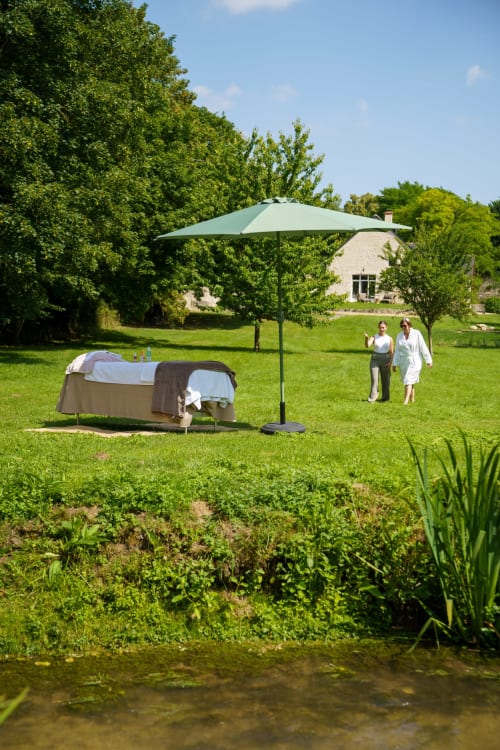 Table de massage spa sous parasol vert dans le jardin soigné du Hameau de Céline, gîte rural en Provence