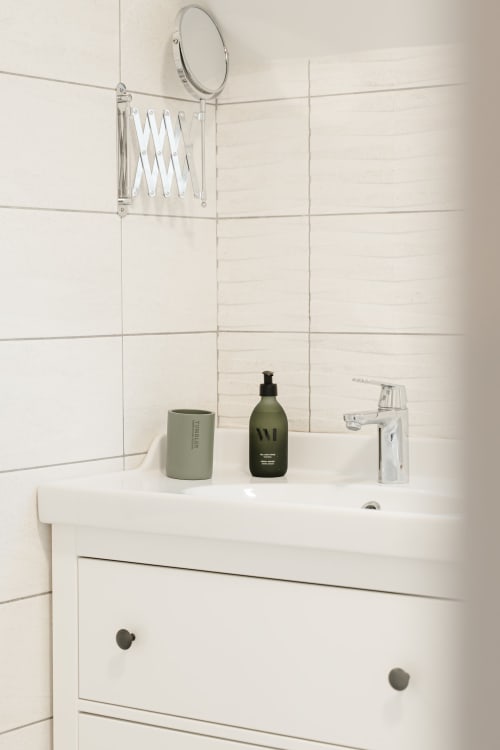 Lavabo moderne du gîte Le Hameau de Céline avec vanité blanche, distributeur de savon vert et miroir rond