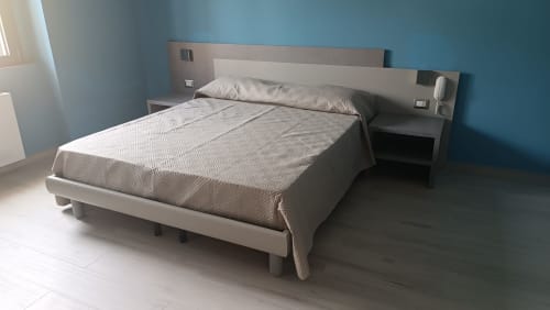 Camera moderna dell'appartamento Amelia Blue a My Home Apulia con letto matrimoniale, pareti blu e testata con comodini integrati