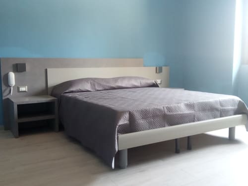 Camera da letto moderna nell'appartamento Amelia Blue di My Home Apulia con biancheria grigia, letto bianco e pareti azzurre
