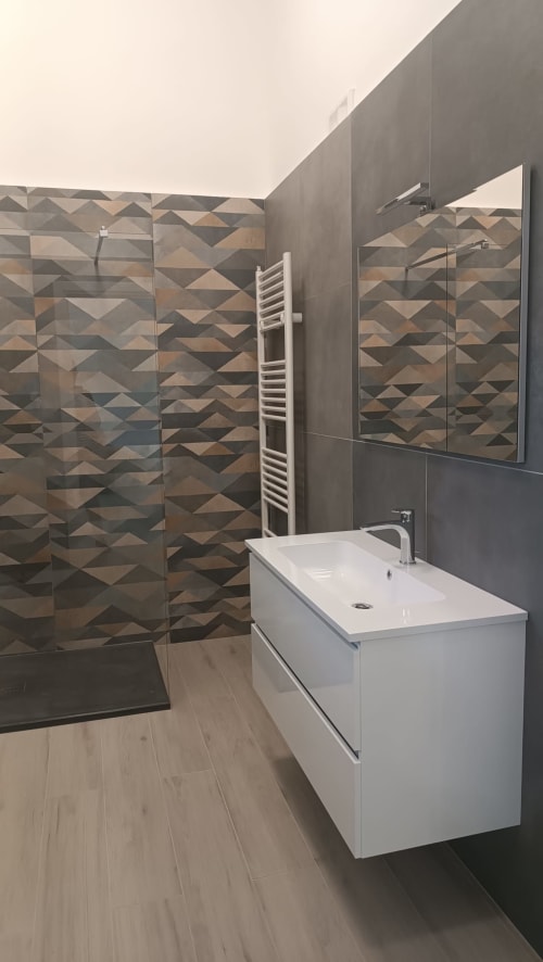 Bagno moderno nell'appartamento Amelia Blue di My Home Apulia con doccia in piastrelle geometriche, vanità bianca e scaldasalviette riscaldato
