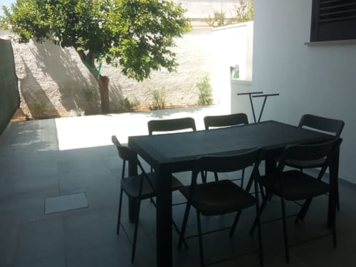 Tavolo da pranzo nero con sedie sulla soleggiata terrazza dell'appartamento My Home Apulia a Veglie, Italia