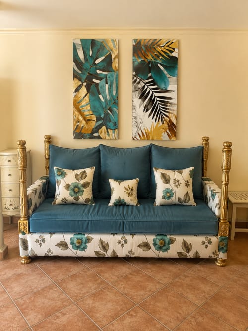 Sofá turquesa elegante con cojines florales en apartamento Misiño, Baiona, con arte botánico dorado y encanto vintage