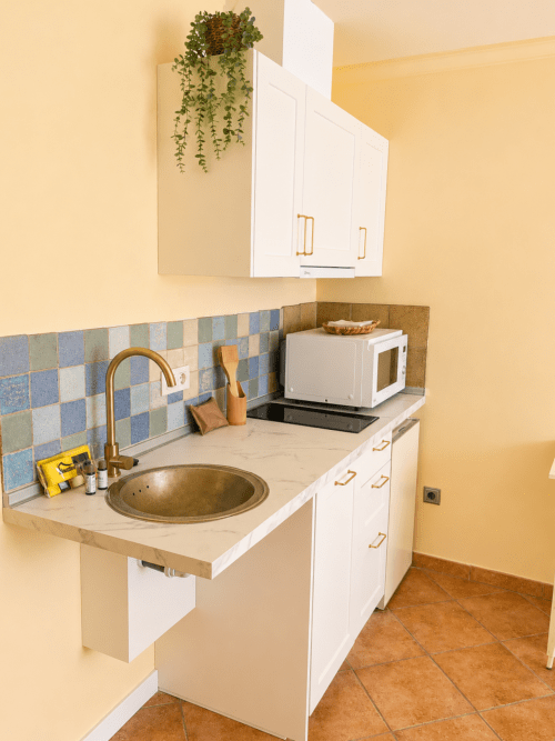 Cocina compacta del apartamento Misiño en Baiona con muebles blancos, azulejos azules, microondas y fregadero redondo