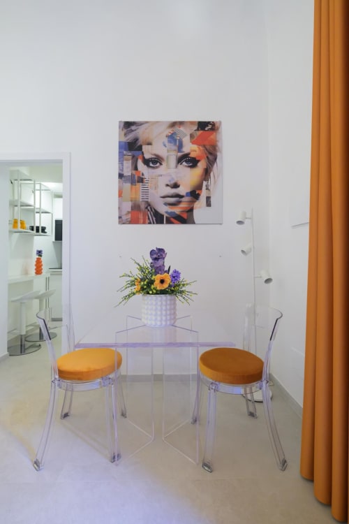 Angolo colazione moderno nella Almatros Rubino Design Suite con sedie trasparenti, opere d'arte colorate e fiori freschi