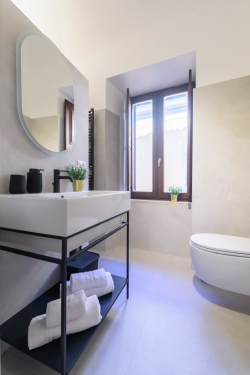 Bagno moderno della Rubino Design Suite all'hotel Almatros di Sulmona, con lavabo bianco, specchio rotondo e ampie finestre
