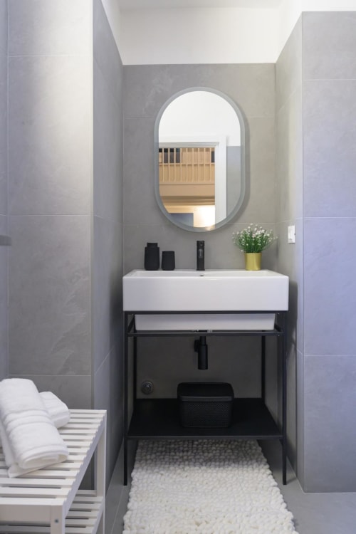 Bagno moderno nella Sulmona Almatros Rubino Design Suite con specchio ovale e vanity nero