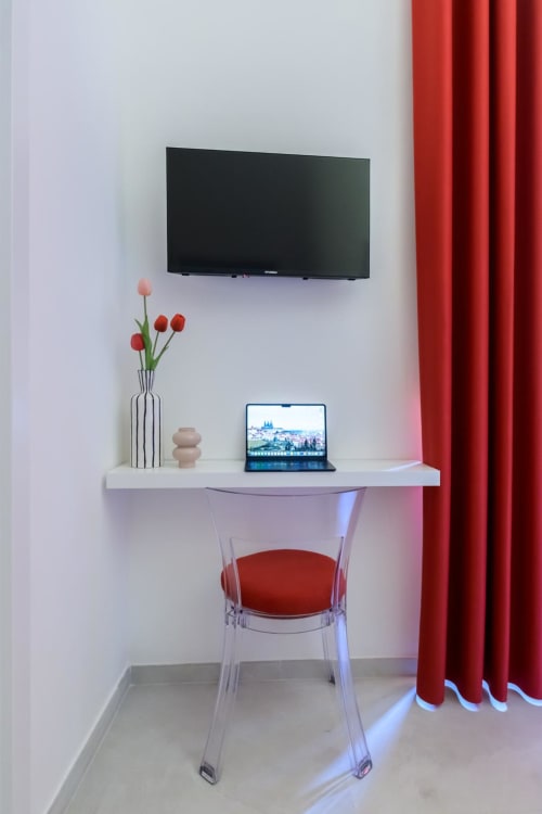 Spazio di lavoro moderno nella Rubino Design Suite dell'hotel Almatros a Sulmona con TV a parete, laptop e accenti rossi
