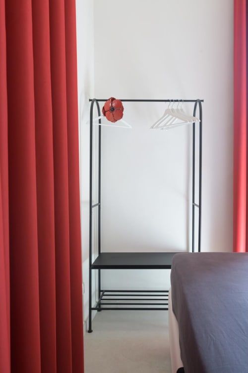 Suite Rubino Design dell'hotel Almatros a Sulmona: appendiabiti nero con grucce bianche e dettagli decorativi rossi