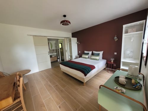 Chambre moderne à la Domaine de la Gare à Mortagne-sur-Gironde avec mur accent bourgogne, lit queen-size et vue sur le jardin