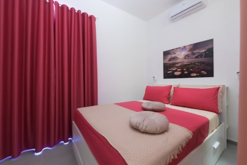 Suite Tormalina del Design presso l'hotel Almatros di Sulmona con biancheria rossa e beige, tende cremisi e paesaggio montano
