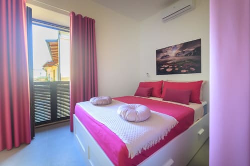 Camera Tormalina Design Suite dell'hotel Almatros a Sulmona con biancheria rosa, accesso al balcone e servizi moderni