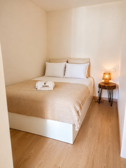 Quarto acolhedor na Terra Clara Studios em Esposende com cama queen, iluminação morna, piso de madeira e decoração minimalista