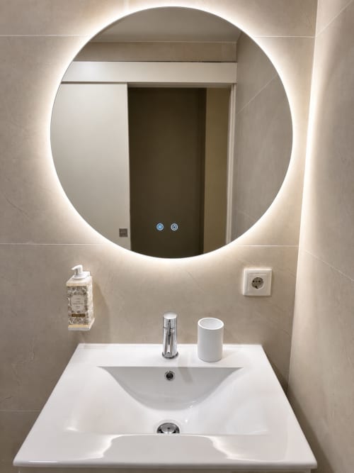 Pia moderna e espelho circular iluminado no estúdio Terra Clara, apartamento em Esposende, Portugal
