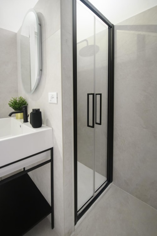 Bagno moderno nelle Almatros Rubino Design Suites a Sulmona con box doccia con cornice nera e specchio rotondo