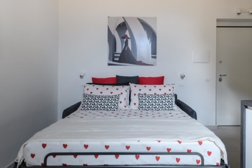 Camera moderna presso Almatros Rubino Design Suites a Sulmona con biancheria a cuori rossi e bianchi e parete contemporanea