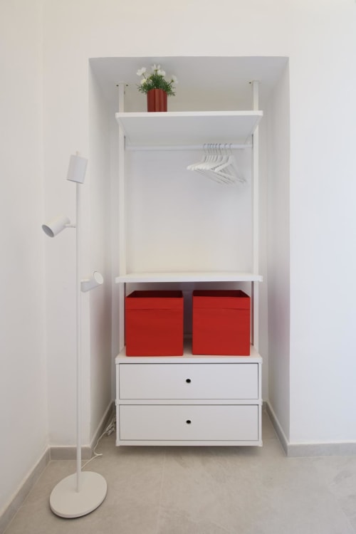 Elegante guardaroba bianco con scatole di stoccaggio rosse e appendiabiti presso Almatros Rubino Design Suites, Sulmona