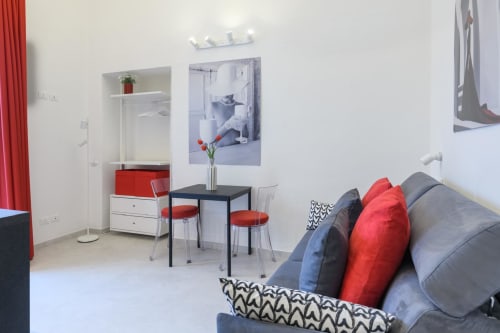 Monolocale Rubino Design Suites ad Almatros Sulmona - studio moderno con divano grigio, dettagli rossi e zona pranzo