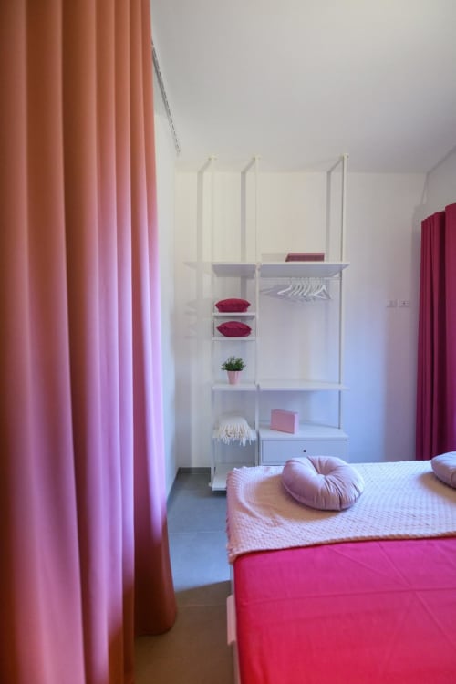 Camera moderna presso Almatros Tormalina Design Suites a Sulmona con tende rosa, ripiani bianchi e biancheria da letto colorata