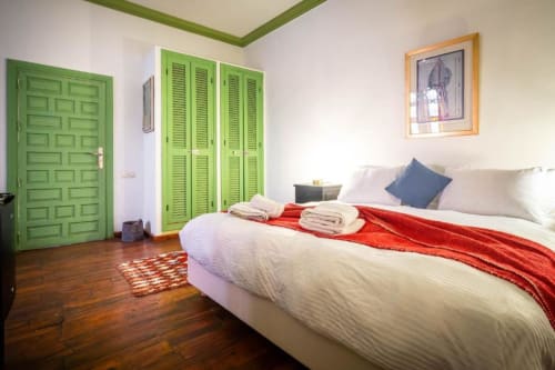 Chambre de la Suite Supérieure à La Villa El Gada à Marrakech avec portes vertes, draps blancs et parquet