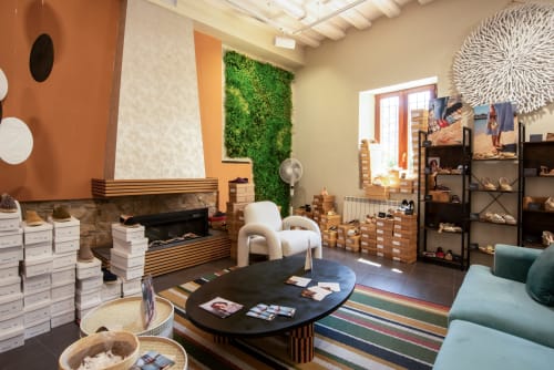Showroom de boutique hotelero moderno con muebles, chimenea, pared verde y vitrinas de productos en Hotel-Boutique by