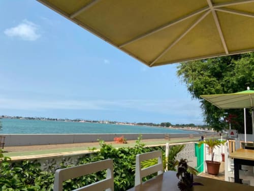 Guarda-sóis amarelos e plantas verdes no terraço à beira-mar do Hotel PZero, com vista para a praia arenosa e baía turquesa de Albufeira.