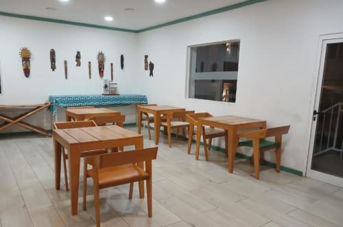Zona de refeições do Hotel PZero em Albufeira com mesas de madeira, cadeiras e máscaras tribais africanas em paredes brancas