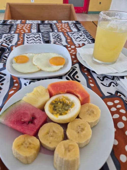 Prato de café da manhã no Hotel PZero Albufeira com ovos fritos, frutas frescas, fatias de banana e maracujá