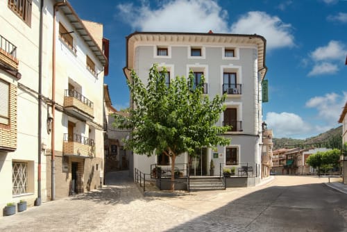 Patio del Hotel-Boutique de Gonzalo Sesma en Cervera del Río Alhama con edificios encalados e hiedra verde