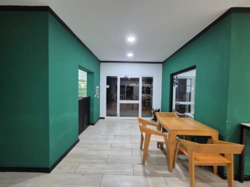 Área de refeições moderna em turquesa no Hotel PZero em Albufeira, com mesa de madeira, cadeiras e portas de vidro