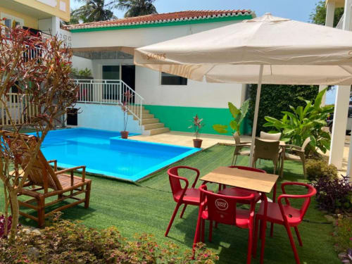 Área de piscina do Hotel PZero em Albufeira com piscina azul, assentos vermelhos e guarda-sóis bege com ambiente tropical