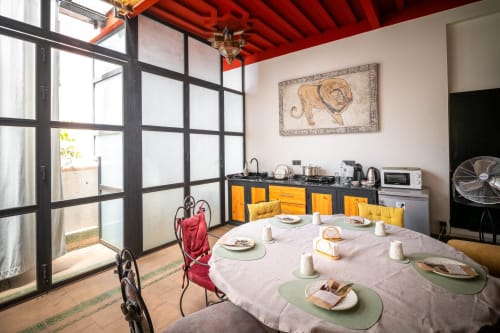 Salle à manger de la Villa El Gada à Marrakech avec table ronde, chaises colorées et plafond rouge vibrant