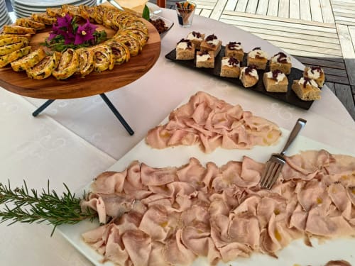 Outdoor catering spread at Hotel Ristorante alle Querce featuring sliced meats, pastries, and appetizers on white tablecloths