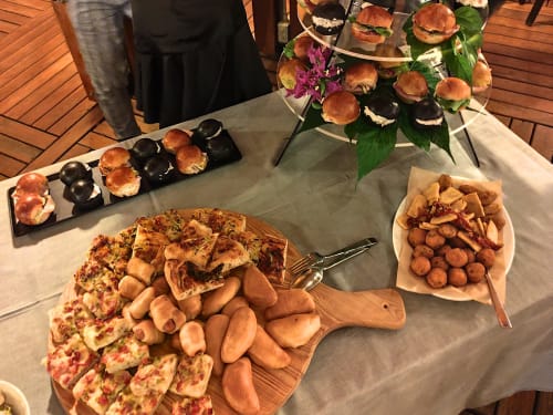 Elegant catered spread at Hotel Ristorante alle Querce in Castelbuono featuring pizza, sliders, and appetizers on wooden
