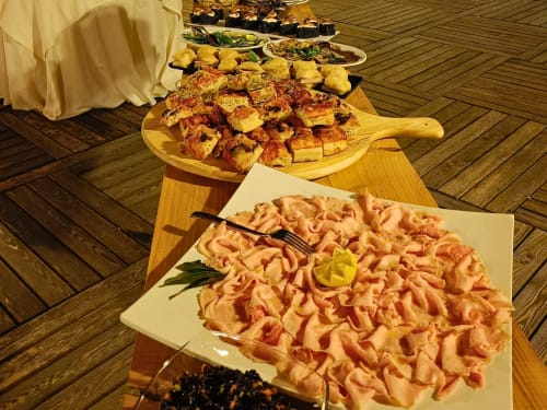 Elegant buffet spread at Hotel Ristorante alle Querce in Castelbuono featuring piped appetizers and roasted meat skewers on