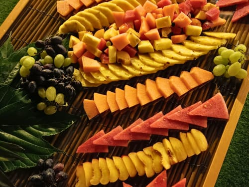 Colorful fruit platter with grapes, melon, and papaya arranged on bamboo tray at Hotel Ristorante alle Querce, Castelbuono