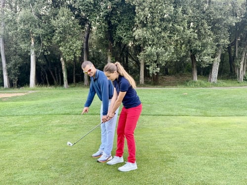 Golf instructor teaching woman proper swing technique on green lawn at STAYnGOLF, Cagnes sur Mer