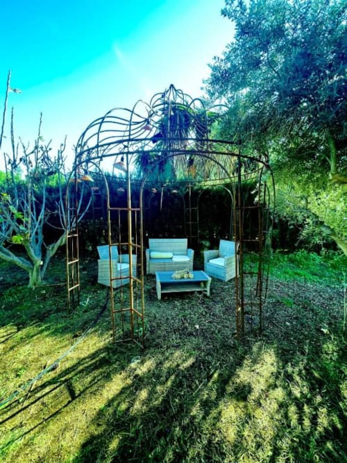 Pérgola metálica azul con zona de estar en exuberante jardín de Villa Magos, alojamiento boutique en Málaga