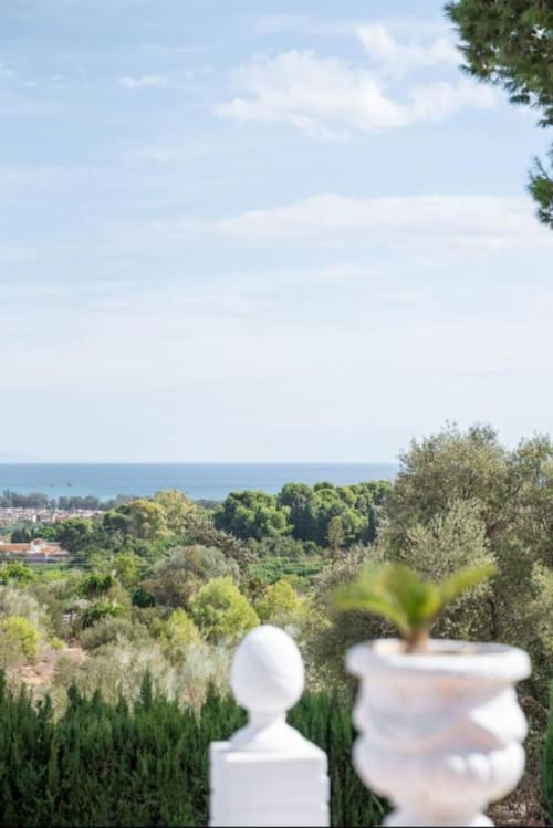 Vista de la terraza Villa Magos con vistas al mar Mediterráneo, jardines de Málaga y paisaje costero con urnas blancas decorativas