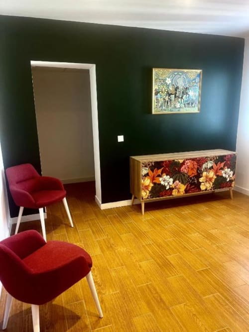 Elegante sala de estar de villa moderna en VILLA MAGOS Málaga con sillas de terciopelo rojo, pared de acento oscuro, aparador floral y detalles de madera