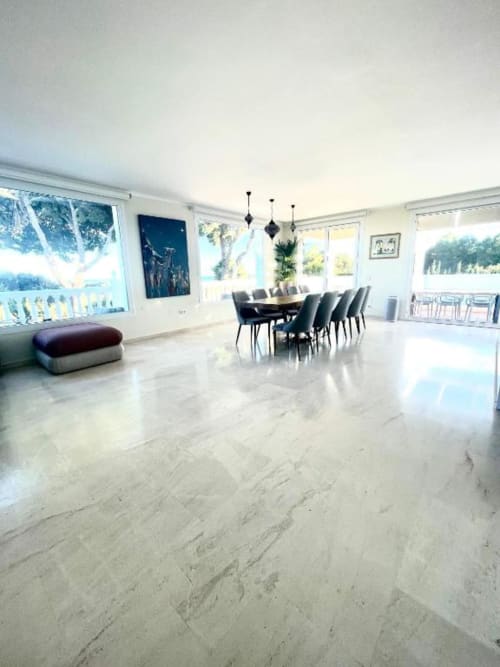 Amplio comedor de villa con pisos de mármol, vistas al mar, mesa de comedor e iluminación moderna con lámparas negras colgantes en Málaga, España.