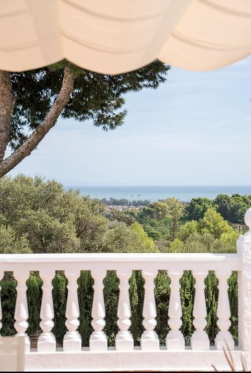 Balcón blanco con balaustradas cubiertas de hiedra con vistas al Mar Mediterráneo, olivos y costa de Málaga en Villa Magos
