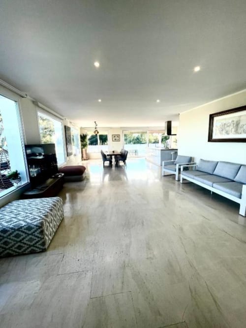 Amplia sala de estar de villa moderna en Málaga con suelos de madera clara, mobiliario contemporáneo, vistas al océano y acceso a